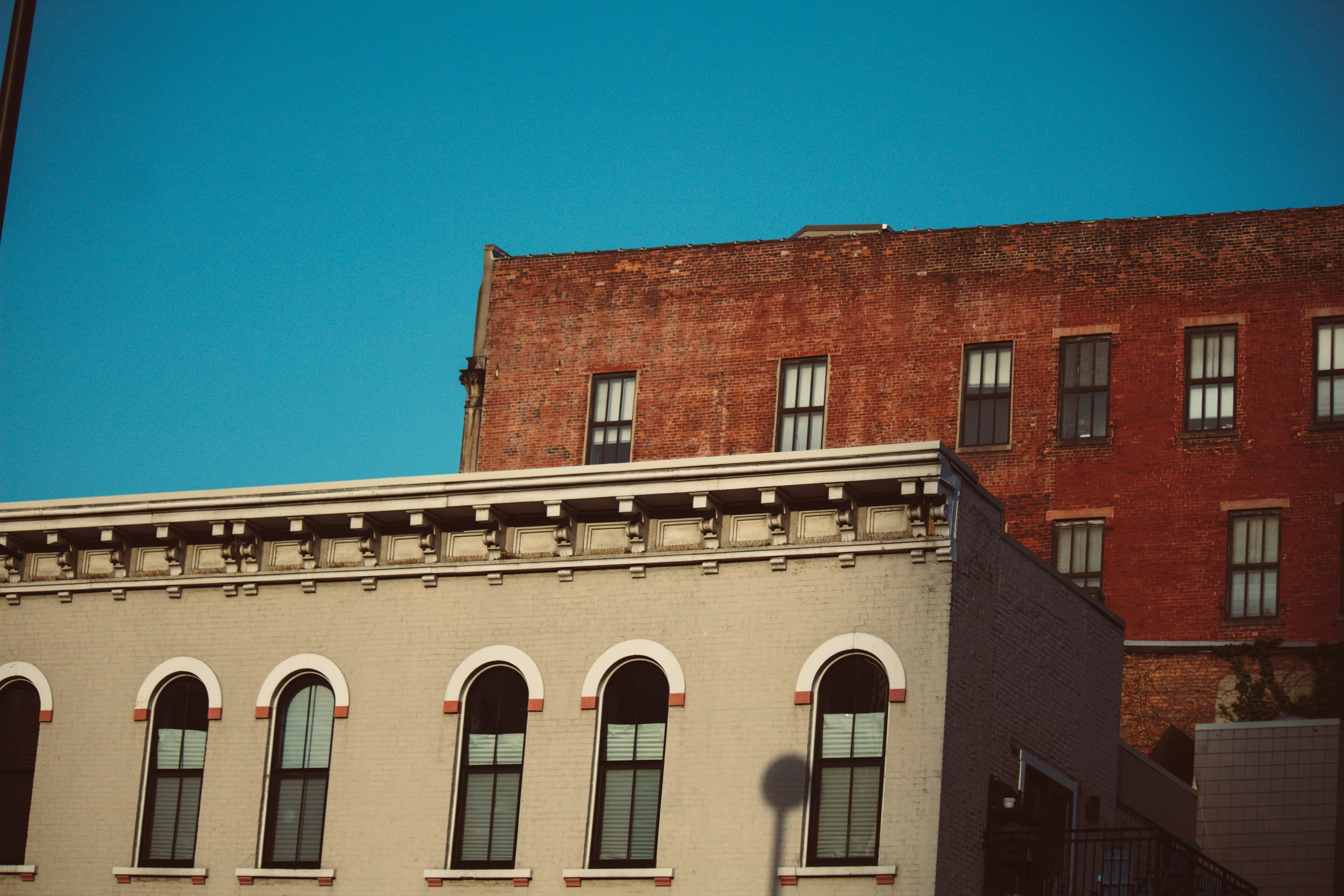 Red brick commercial building next to cream-colored storefront at dusk